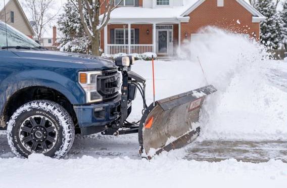 Pickup truck with a snow plow clearing a home driveway